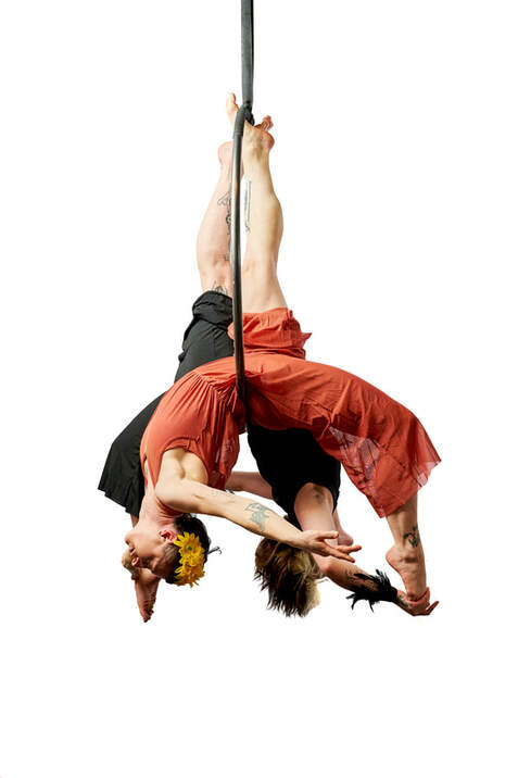 Two women on a hoop, one in black and one in orange, holding a symmetrical back balance pose